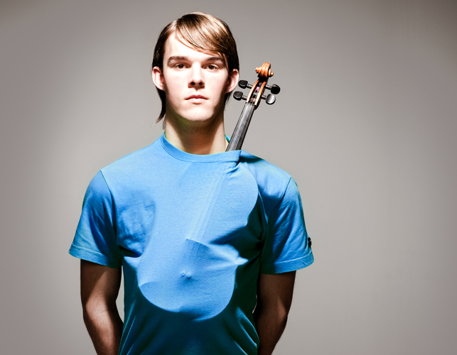 Jongen met een een blauw shirt met daaronder een viool die er aan de bovenkant uit steekt