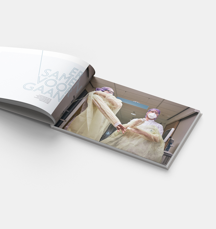 Opengevouwen boek met een foto van twee mensen in ziekenhuis kleding en bescherming en de tekst: er samen voor gaan